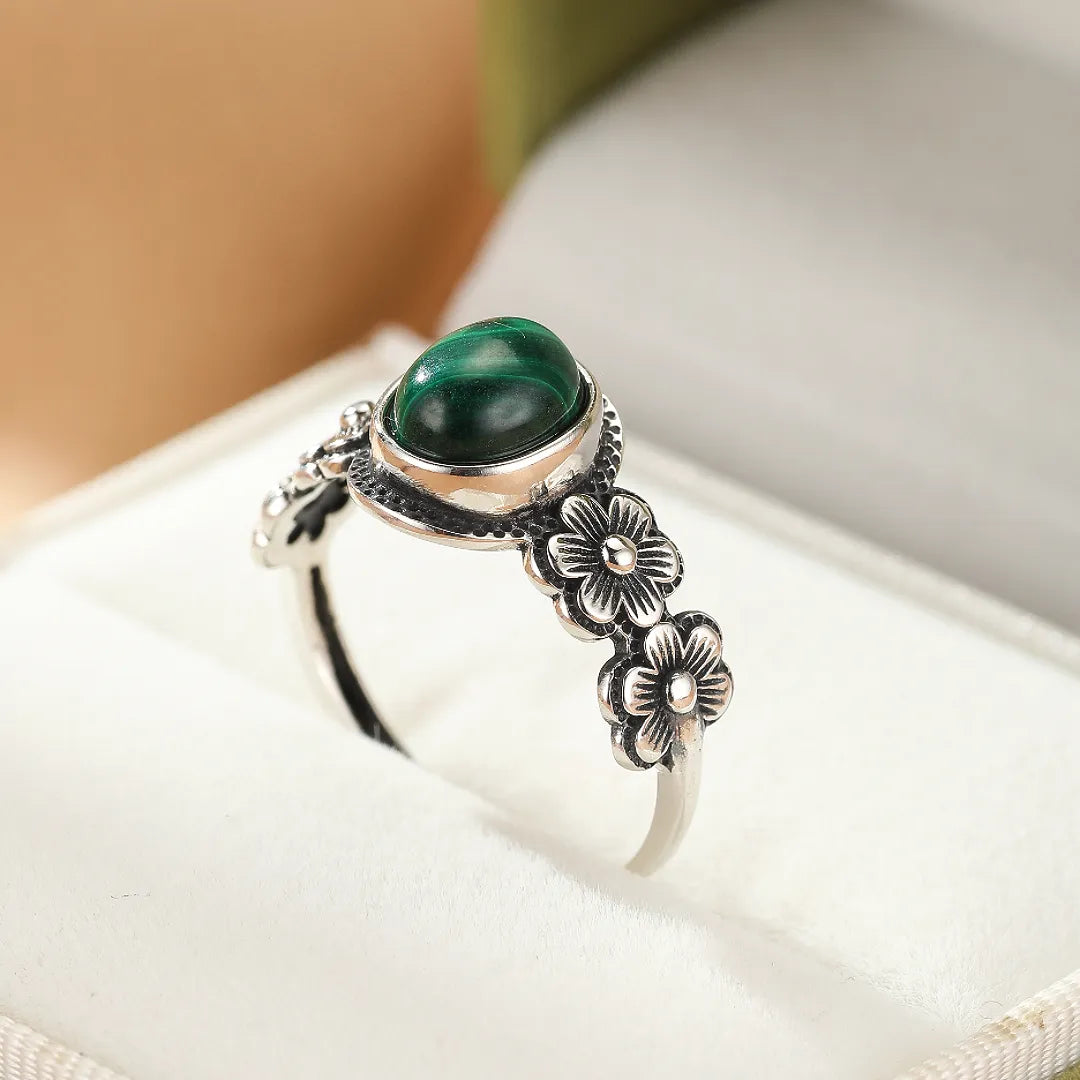 Bague en argent ornée d'une malachite verte ovale et de motifs floraux délicats sur l'anneau.