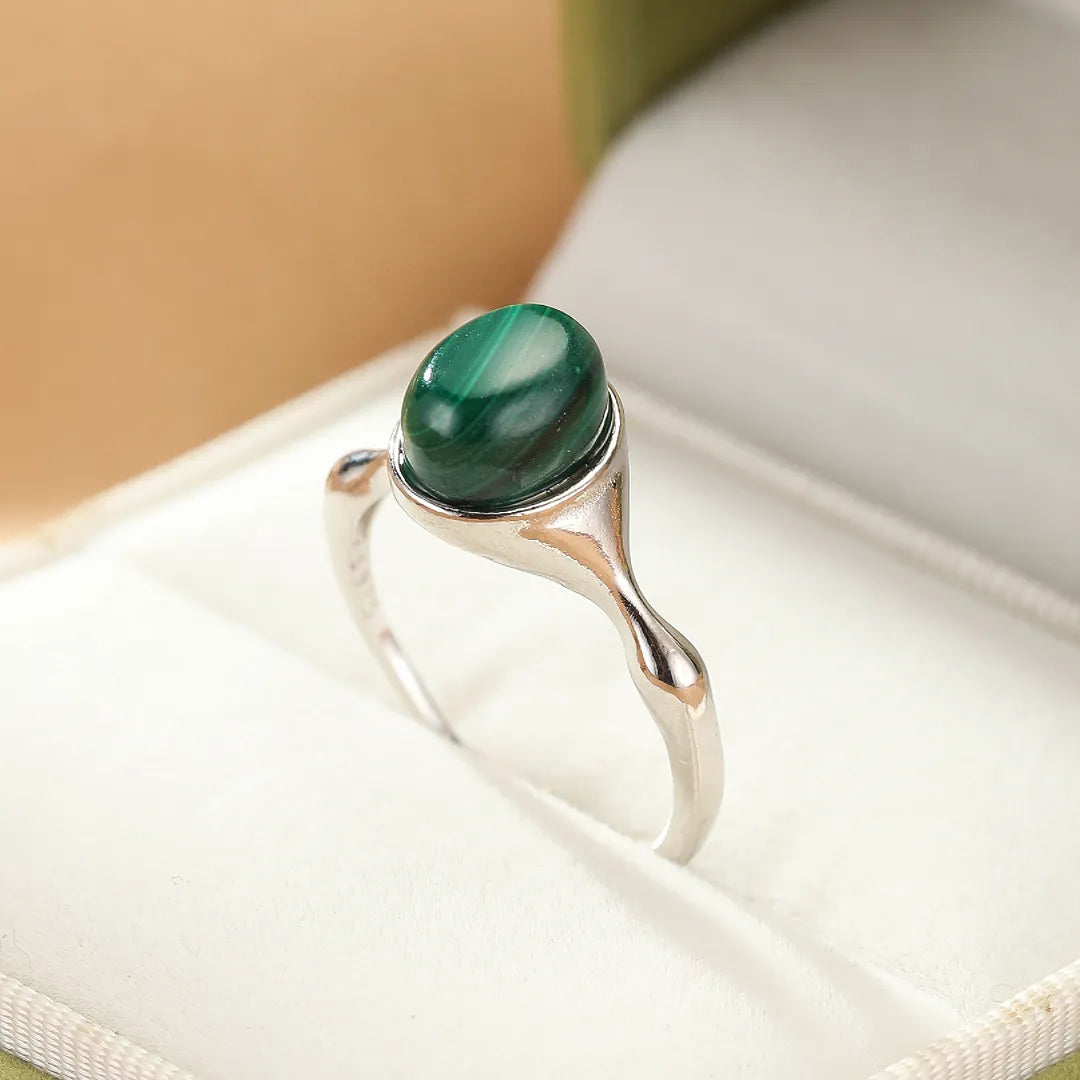 Bague en argent avec une pierre de malachite verte aux motifs naturels de transformation, présentée dans un écrin.