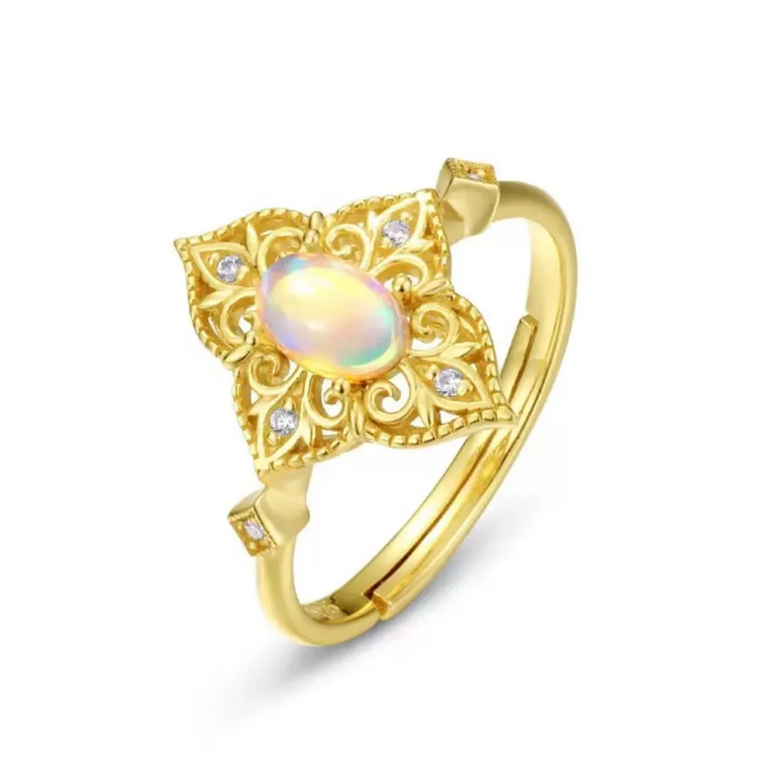 Bague en argent doré 10K avec une opale ovale centrale entourée de motifs floraux ajourés et de petites pierres scintillantes.