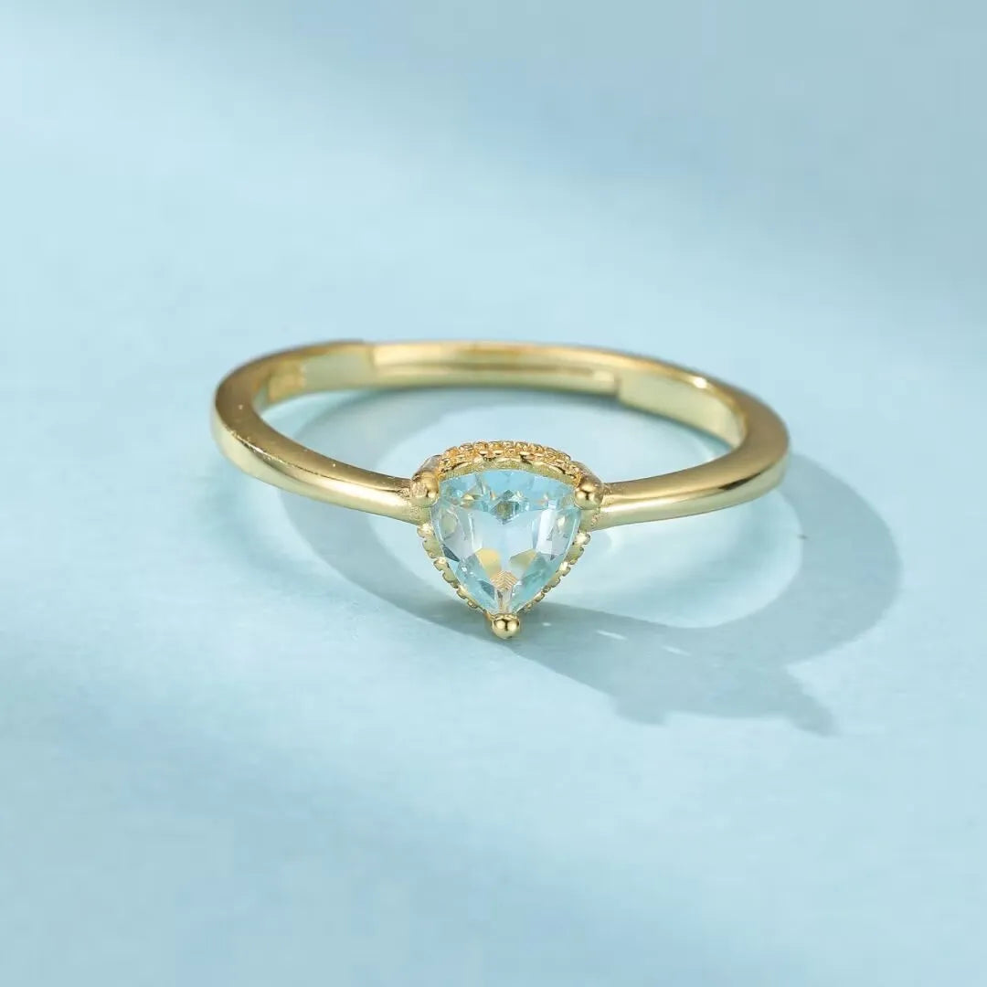 Bague ajustable en argent doré or 18K avec une topaze bleue en forme de cœur, sertie sur un anneau fin.