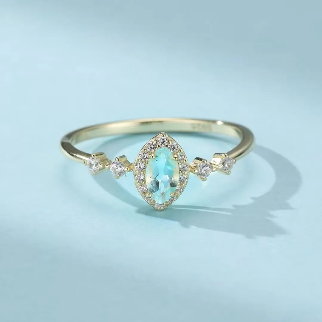 Bague en argent 925 sertie d'une topaze bleue en forme de marquise, entourée de petits zirconiums scintillants.