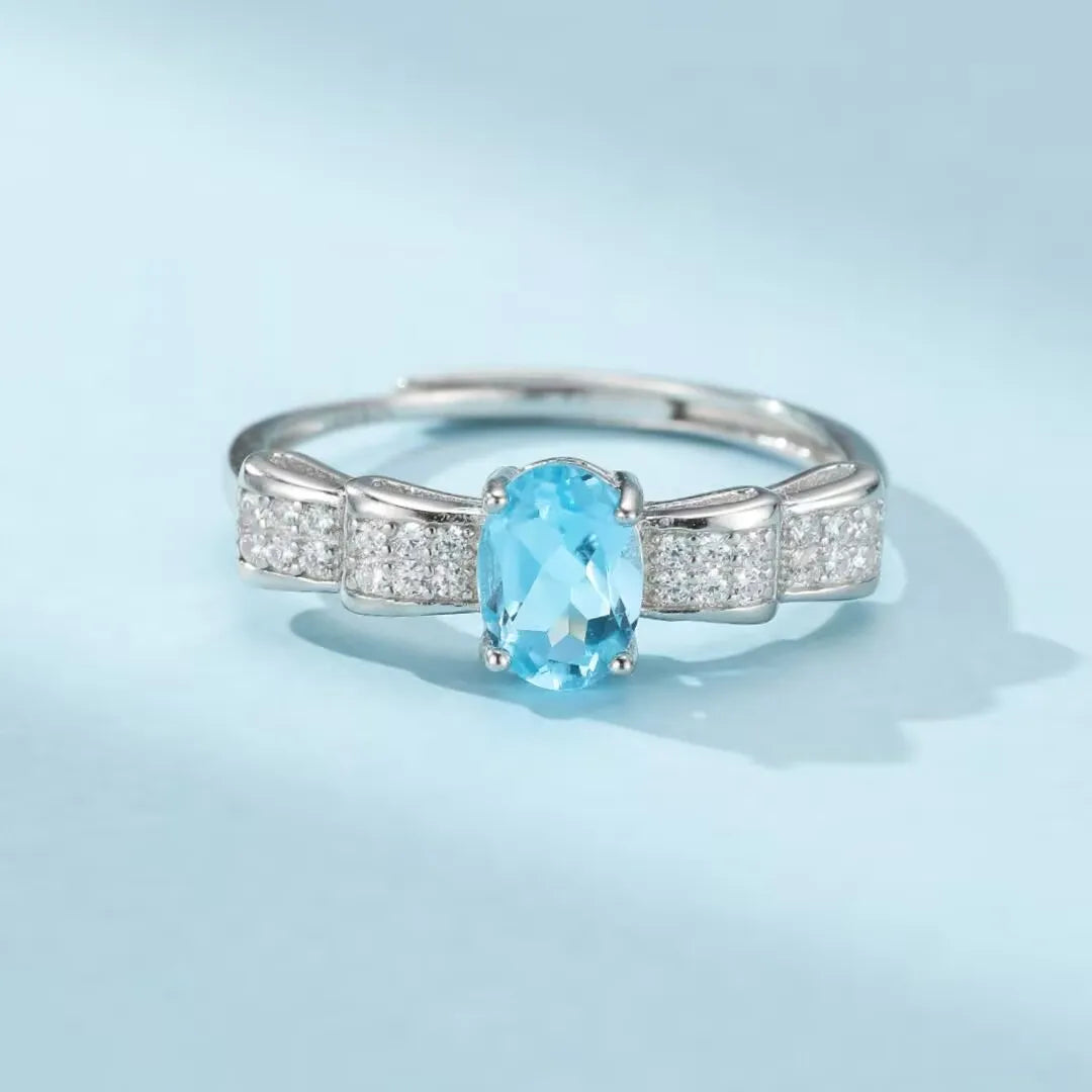 Bague en argent 925 sertie d'une topaze bleue ovale et de zircons cubiques, design nœud papillon.