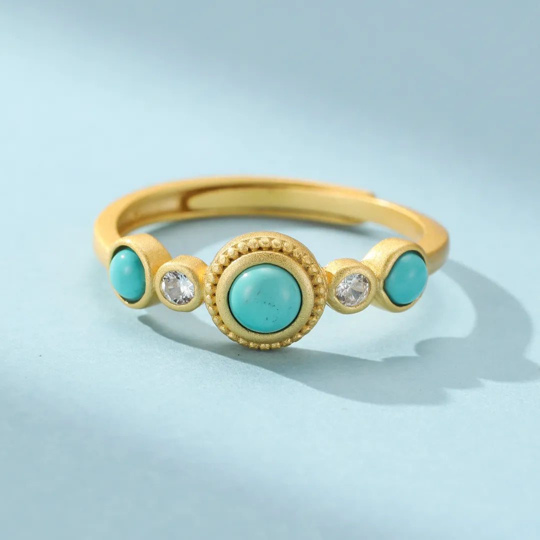 Bague ajustable en argent doré ornée d'une turquoise centrale entourée de deux petites turquoises et de deux zircons blancs, style bohème chic.
