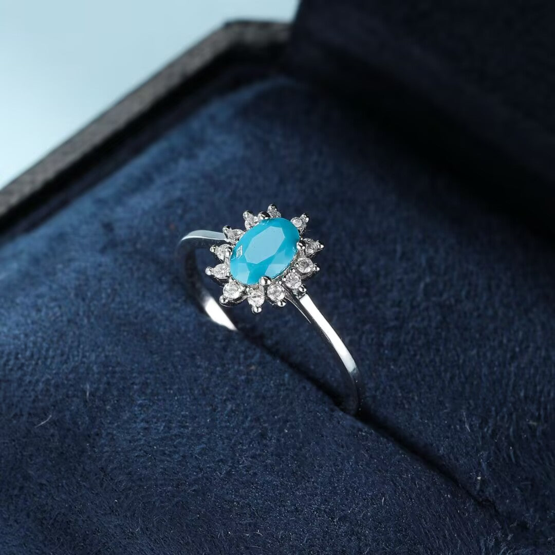 Bague en argent 925 avec une turquoise ovale bleue ciel entourée de petites pierres scintillantes, évoquant une fleur marine.