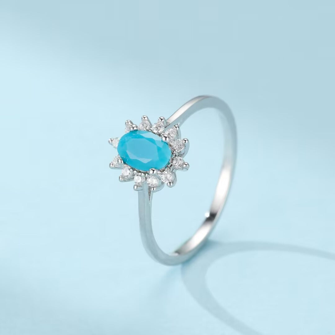 Bague en argent 925 avec une turquoise ovale bleue entourée de petits zircons blancs, style fleur marine.
