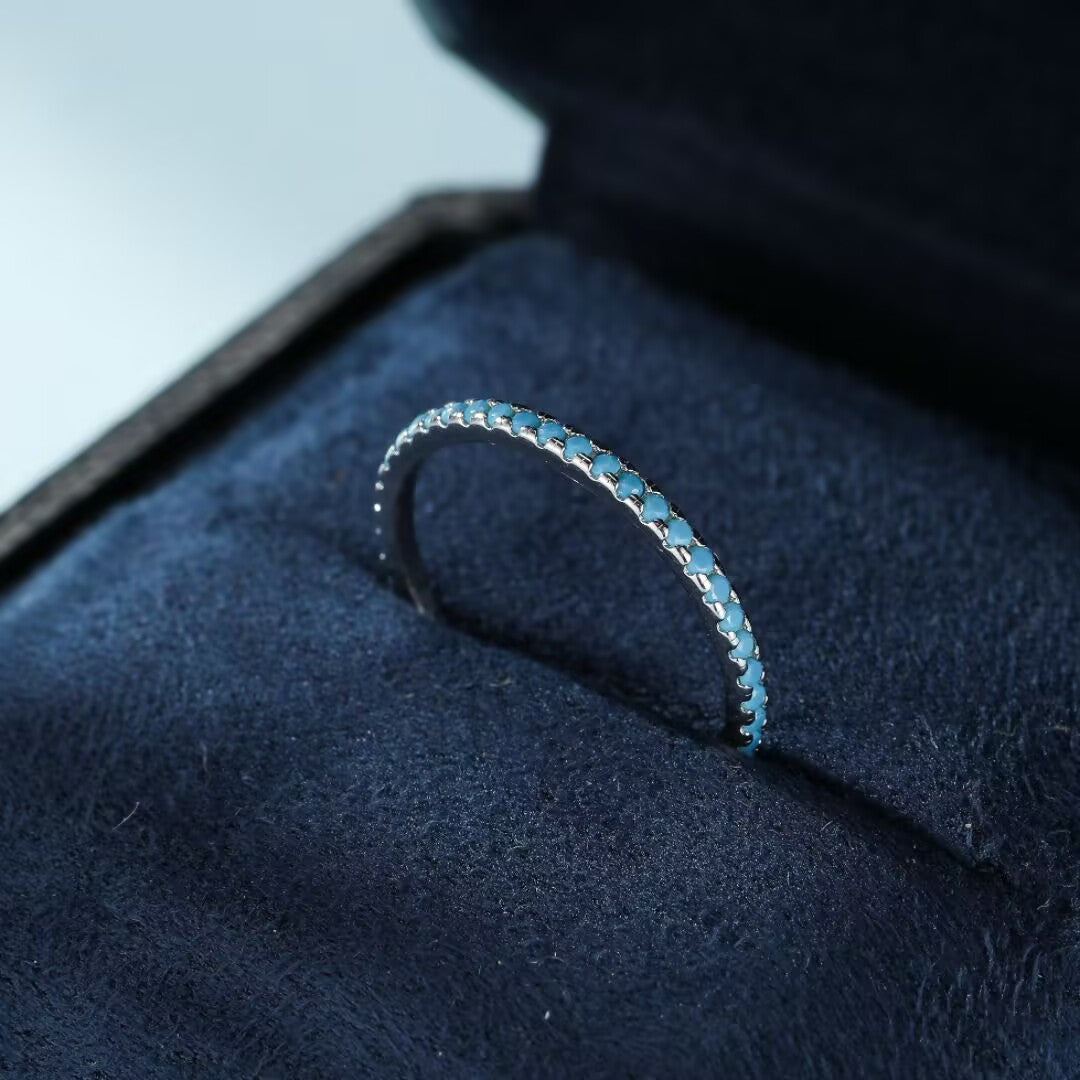 Bague fine en argent 925 incrustée de petites pierres turquoise bleues, présentée dans son écrin.