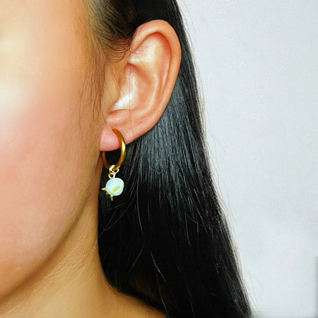 Boucle d'oreille créole dorée avec une petite pierre blanche nacrée en forme d'étoile pendant.