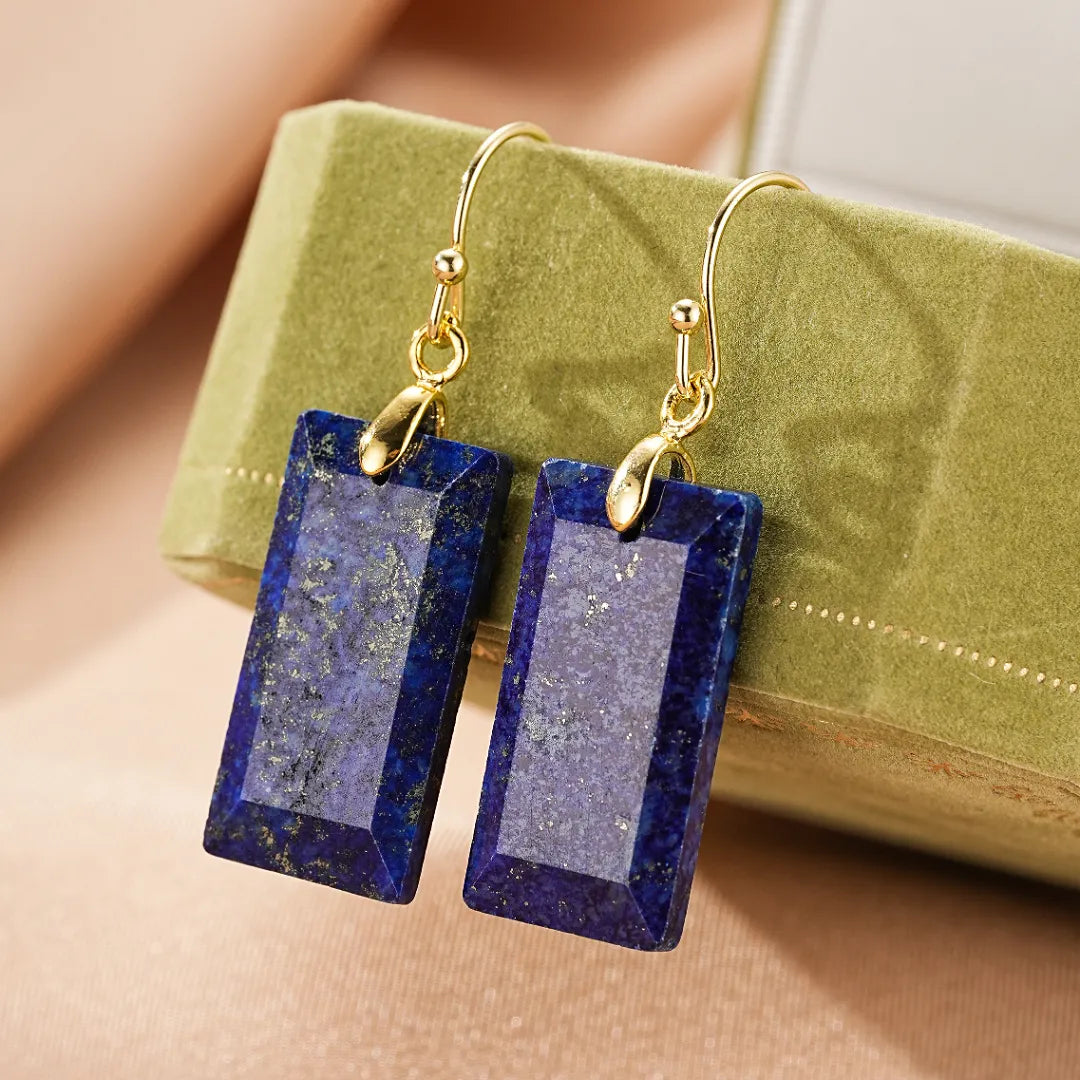 Boucles d'oreilles rectangulaires en lapis-lazuli avec monture dorée, présentées sur un coffret vert.