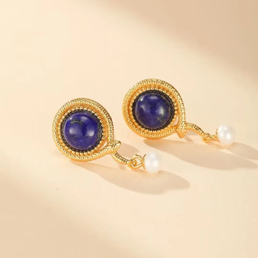 Boucles d'oreilles serpent en argent doré ornées de lapis lazuli et de perles blanches, inspirées par la sagesse pure.