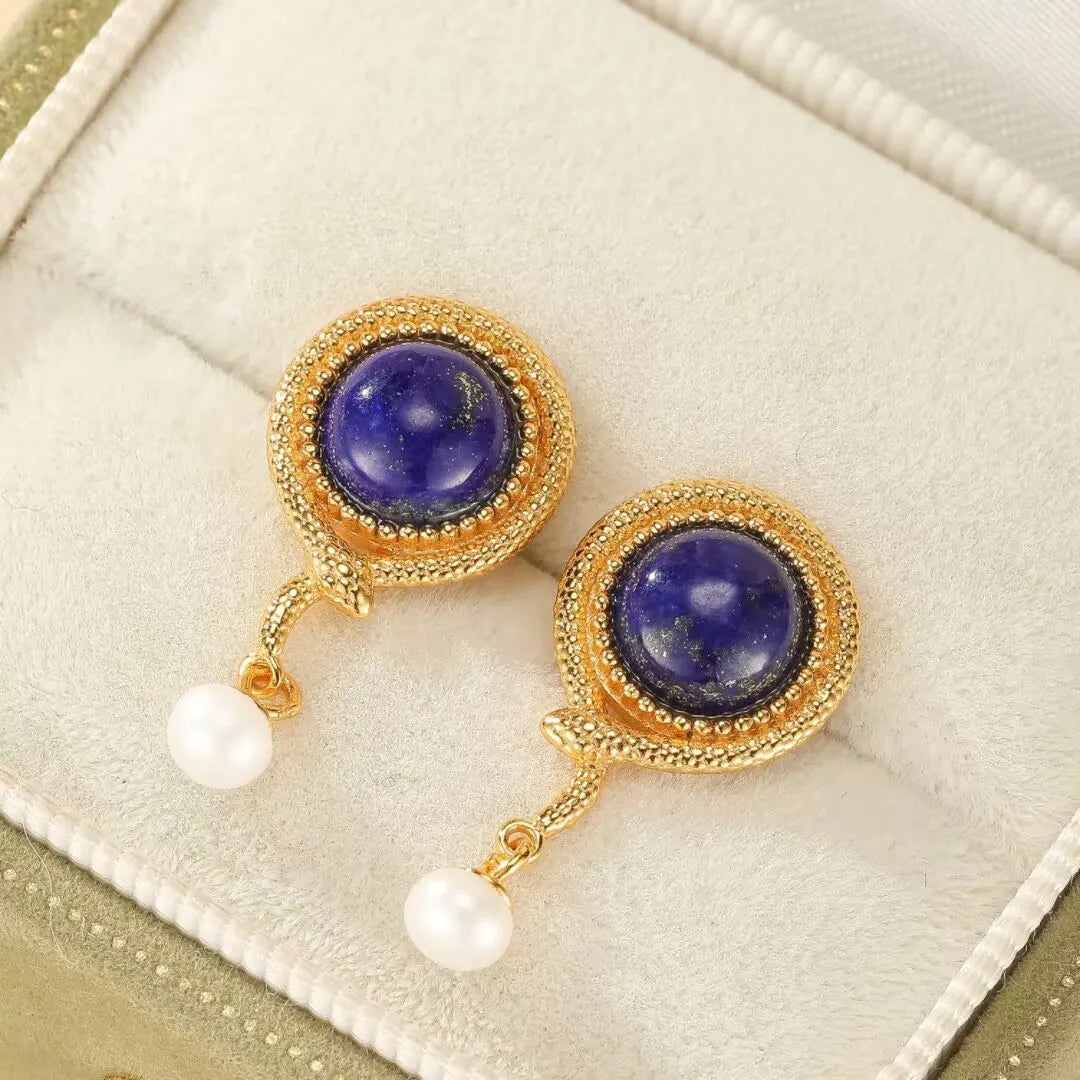Paire de boucles d'oreilles pendantes en argent doré ornées d'un cabochon rond en lapis lazuli bleu intense et d'une perle blanche suspendue, avec un design en forme de serpent.