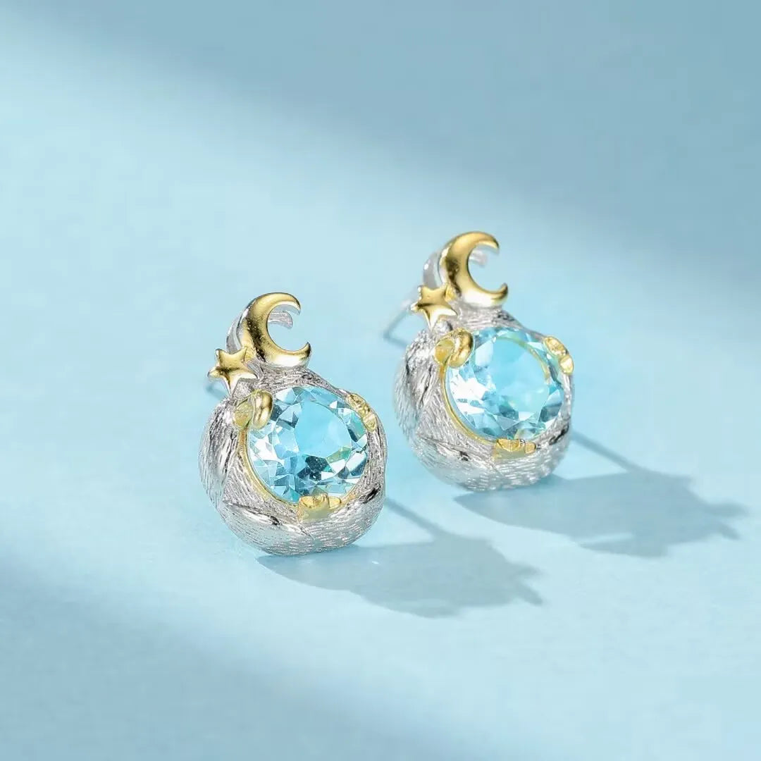 Boucles d'oreilles en argent 925 ornées de topazes bleues rondes et de motifs en forme de croissant de lune et d'étoiles dorées, style céleste.