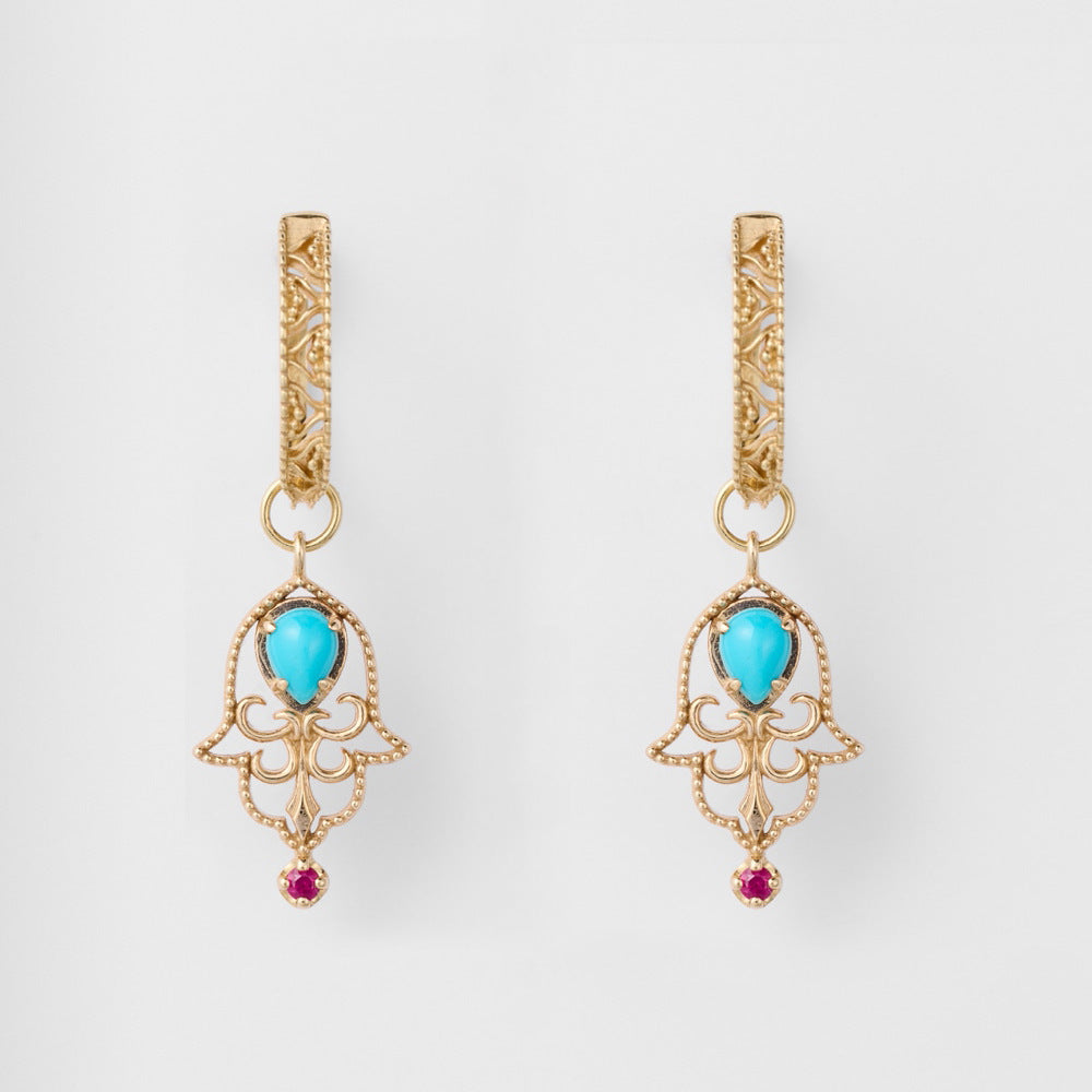 Boucles d’oreilles "Aura Ancestrale" en argent doré, ornées d'une turquoise en forme de goutte et d'une petite pierre rouge au centre, sur fond blanc.