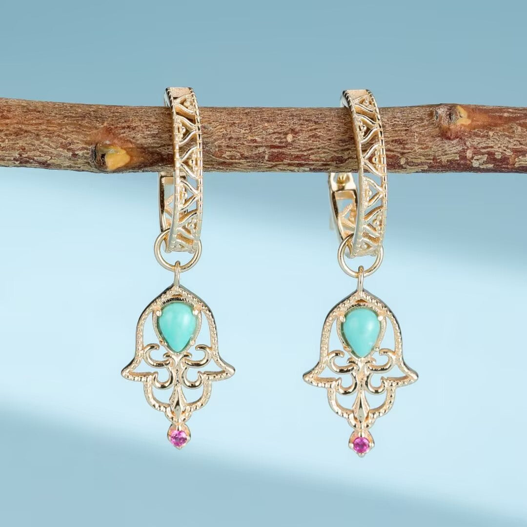 Paire de boucles d'oreilles "Aura Ancestrale" en argent doré or, ornées de turquoises et de petites pierres roses, suspendues à une branche.