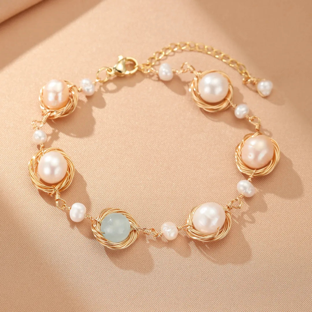 Bracelet "Mer Douce" en or avec des perles roses et blanches et une pierre d'aigue-marine centrale, monté sur un fil métallique torsadé.