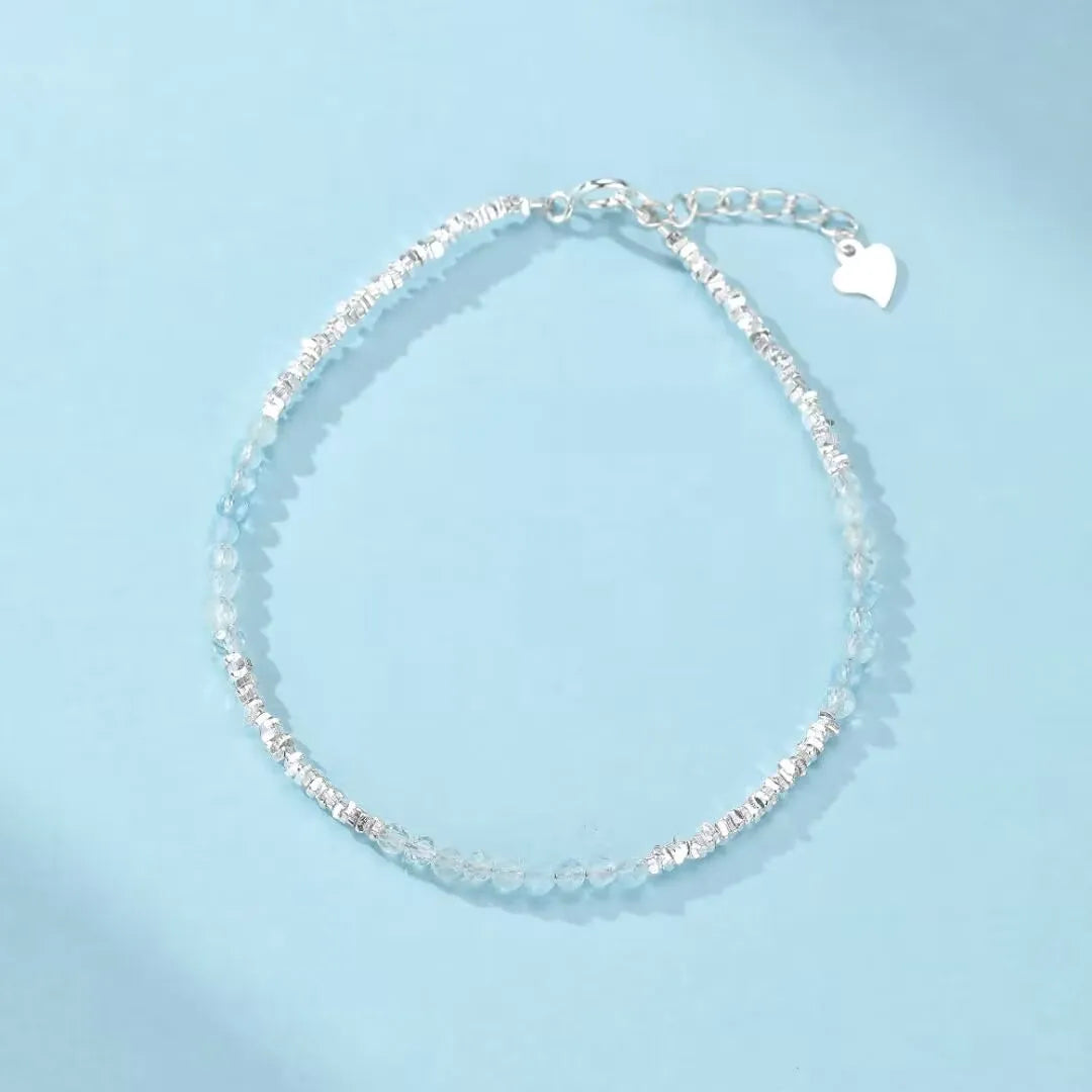 Bracelet "Murmure Douce" en argent avec des pierres d'aigue-marine bleues claires et une breloque en forme de cœur.