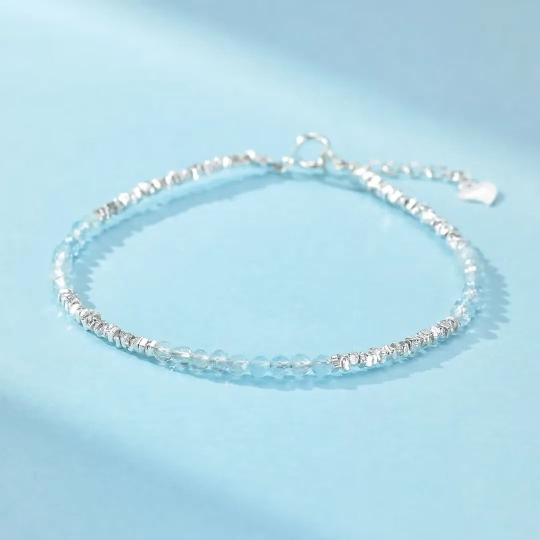 Bracelet fin en argent 925 avec des petites pierres d'aigue-marine facettées et des éléments argentés texturés, fermoir mousqueton.