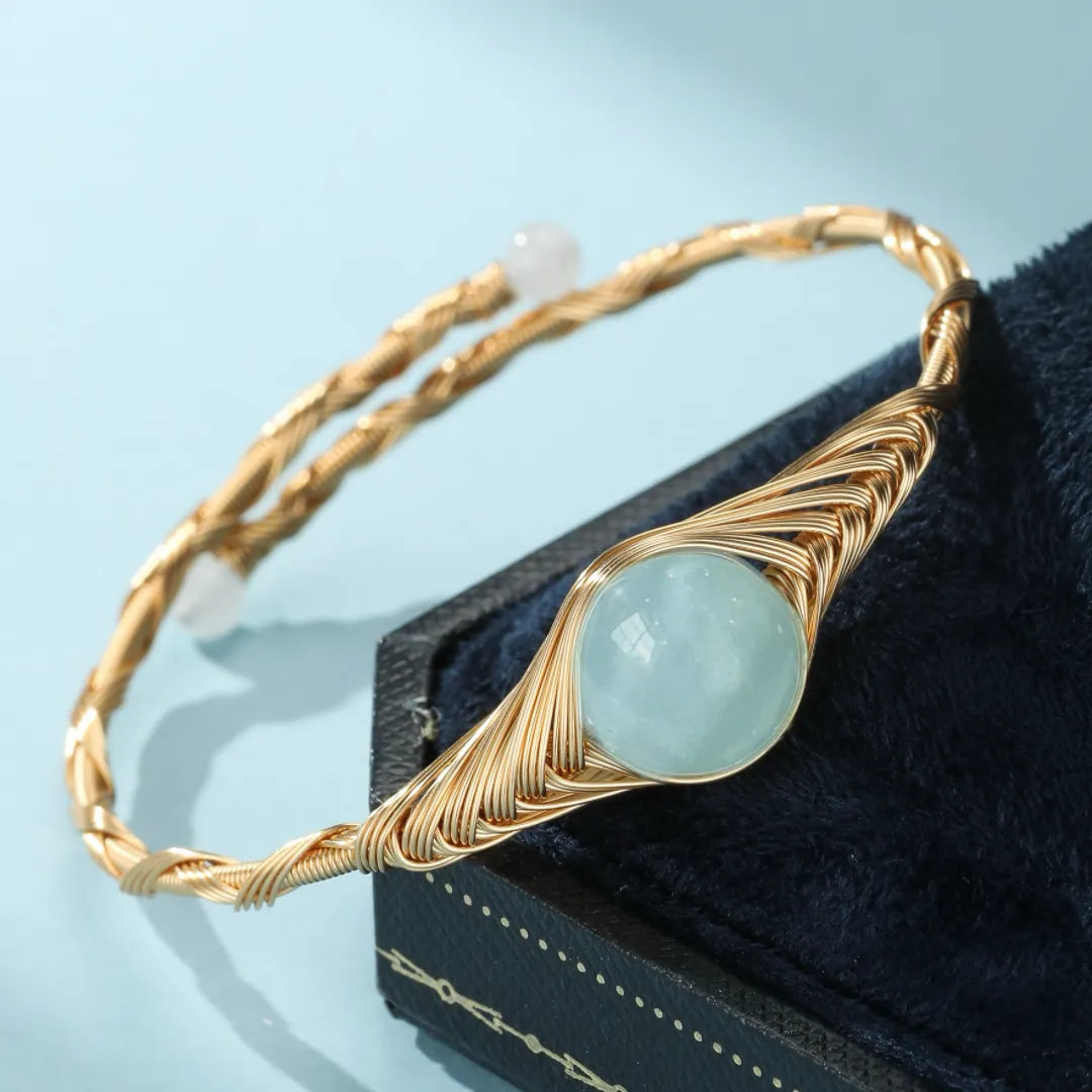 Bracelet jonc doré or 14K avec une pierre d'aigue-marine ronde centrale et deux petites perles blanches aux extrémités, monté sur une monture torsadée