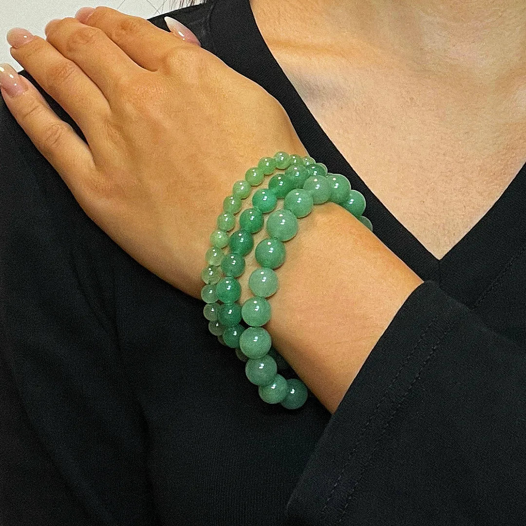 Trois bracelets en perles d'aventurine verte de différentes tailles, portés sur le poignet d'une femme.