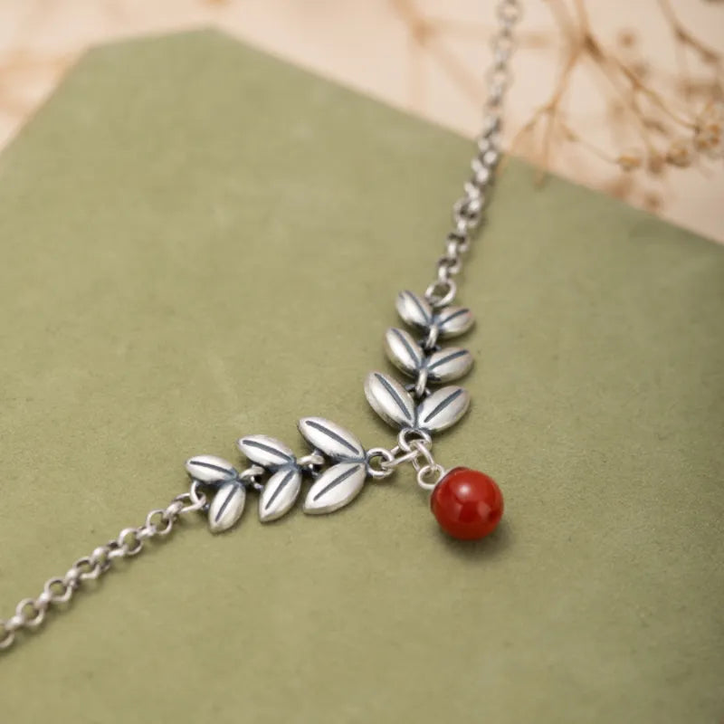 Bracelet de cheville en argent orné de feuilles stylisées et d'une petite perle rouge
