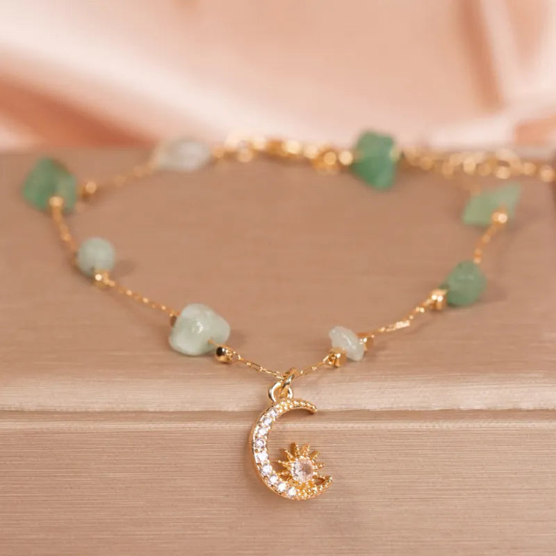 Bracelet de cheville "Brise Céleste" en aventurine verte et quartz rose, avec un pendentif lune et soleil orné de cristaux scintillants.