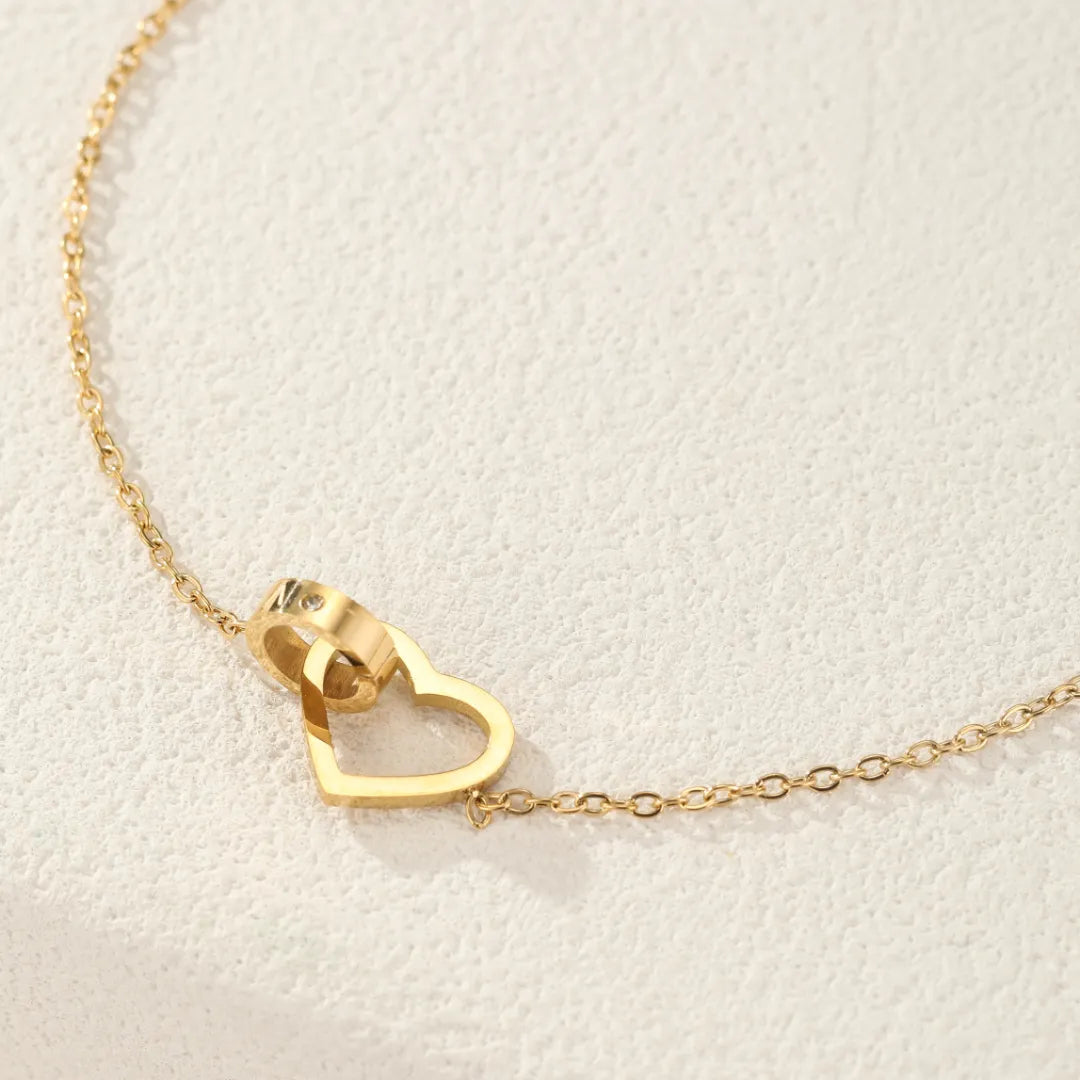 Bracelet de cheville doré avec un pendentif en forme de cœur entrelacé avec un anneau.