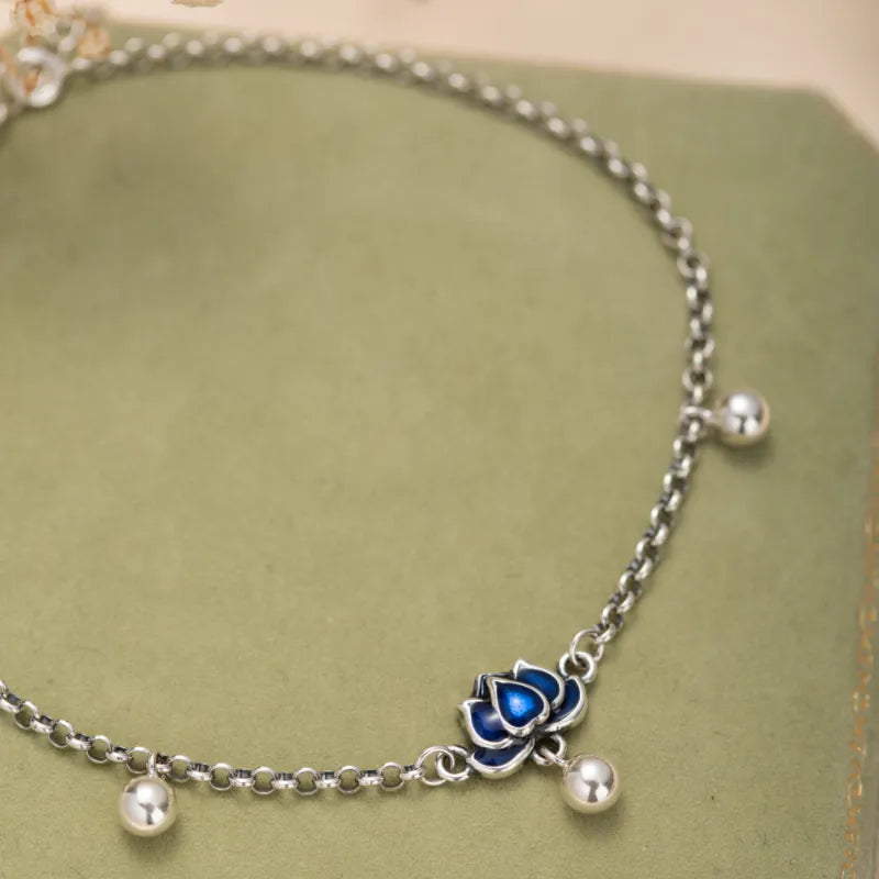 Bracelet de cheville en argent avec un charme de fleur de lotus bleue et de petites billes argentées.