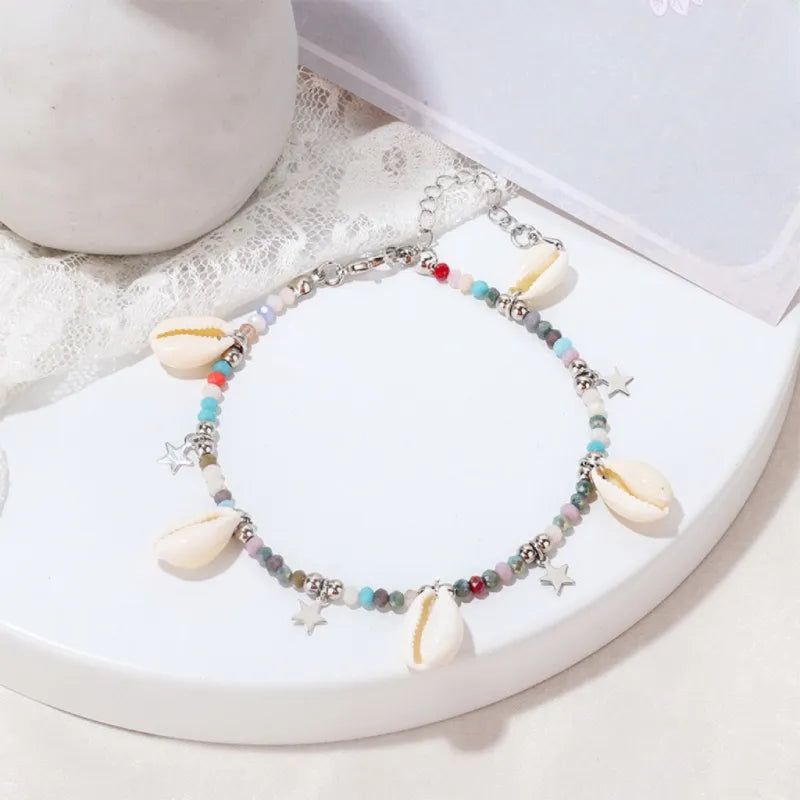 Bracelet de cheville "Brise Marine" orné de coquillages, étoiles et perles multicolores sur une chaîne argentée.