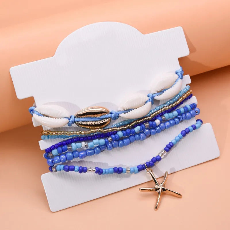 Ensemble de bracelets de cheville "Énergie Marine" ornés de coquillages et d'une étoile de mer dorée, avec des perles bleues de différentes tailles et des accents dorés.