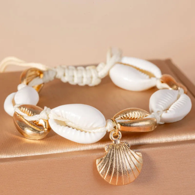 Bracelet de cheville artisanal en coquillages blancs et dorés avec un pendentif coquillage, style bohème chic et marin.