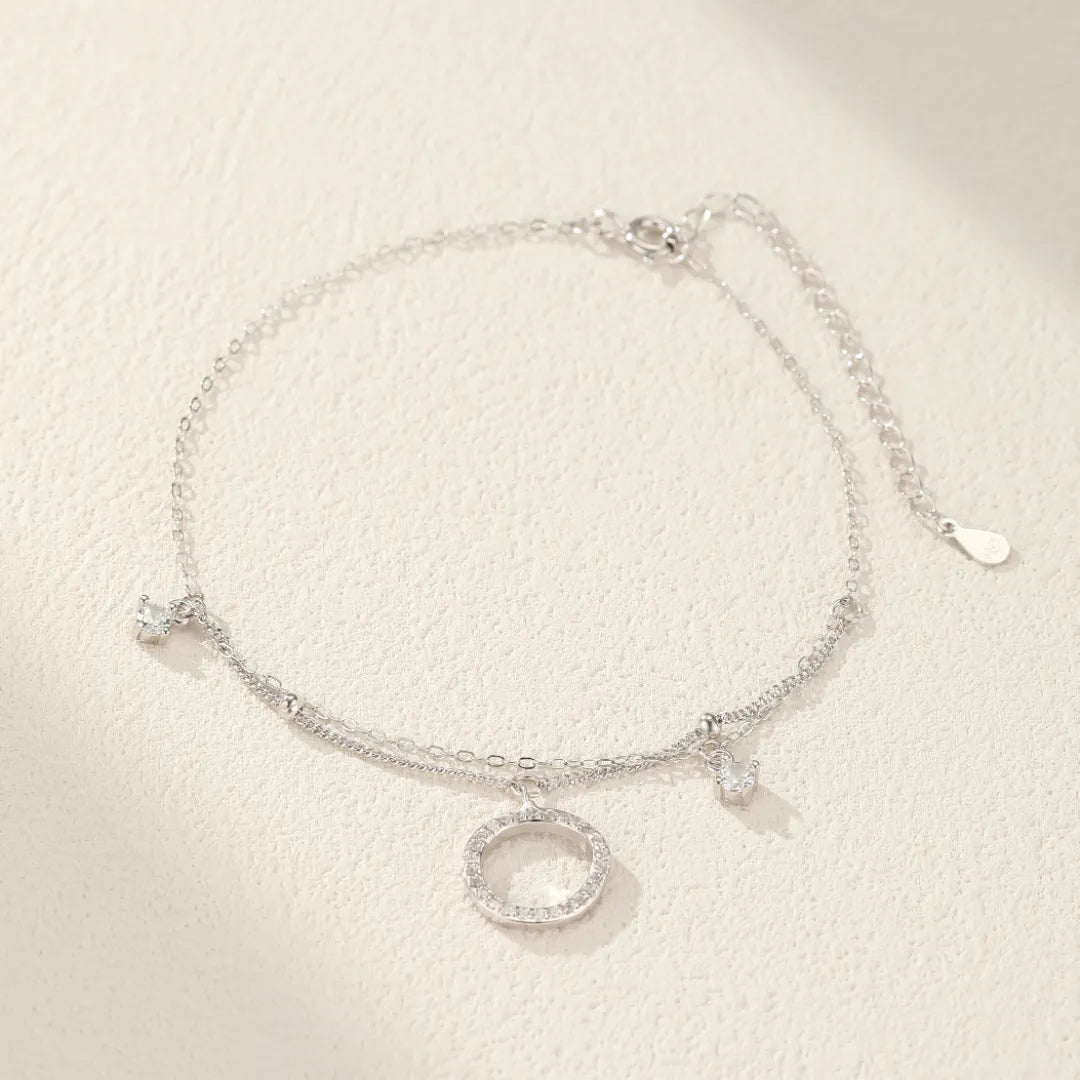 Bracelet de cheville double chaîne en argent orné d'un pendentif cercle pavé de cristaux et d'un petit motif lune ou étoile.