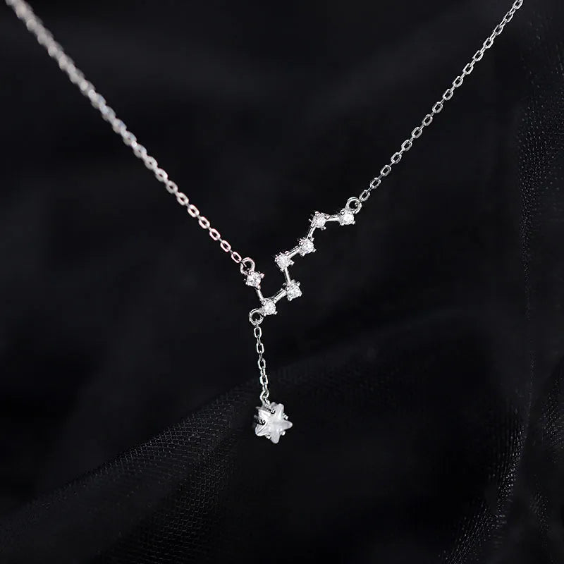Collier constellation étoile en argent 925 avec un pendentif étoile scintillante, sur fond noir.