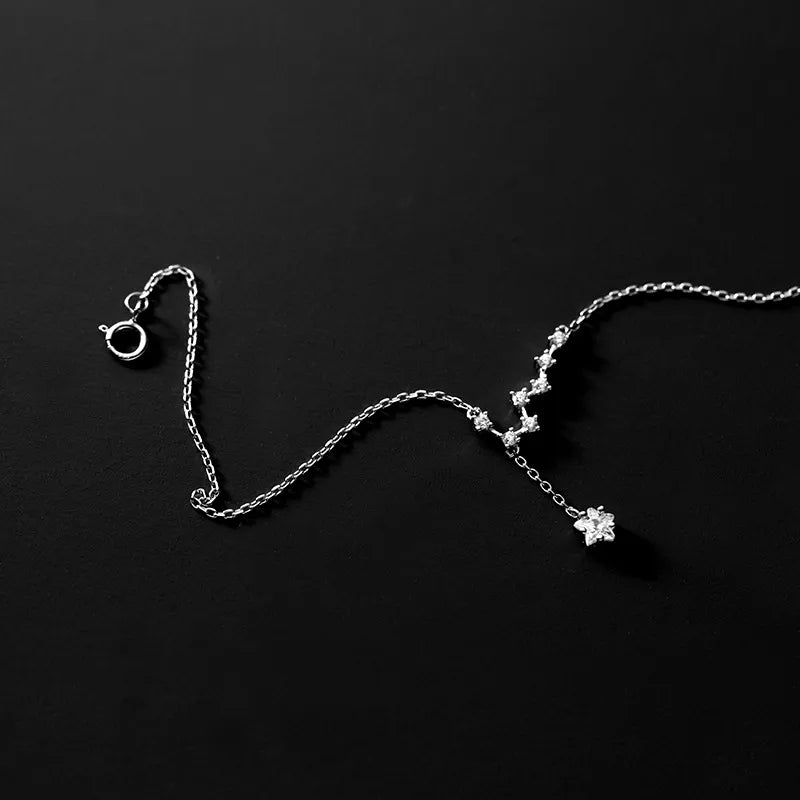 Bracelet de cheville en argent 925 avec une chaîne fine ornée de petites étoiles serties de cristaux scintillants, et un pendentif étoile à l'extrémité.