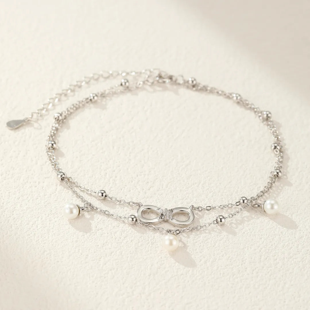 Bracelet de cheville double chaînes argentées "Harmonie Éternelle" orné d'un symbole infini serti de zircons et de perles d'eau douce.