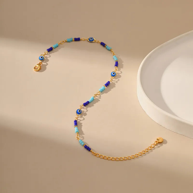 Bracelet de cheville doré or avec perles bleues et breloques œil du destin pour une protection amuletique.