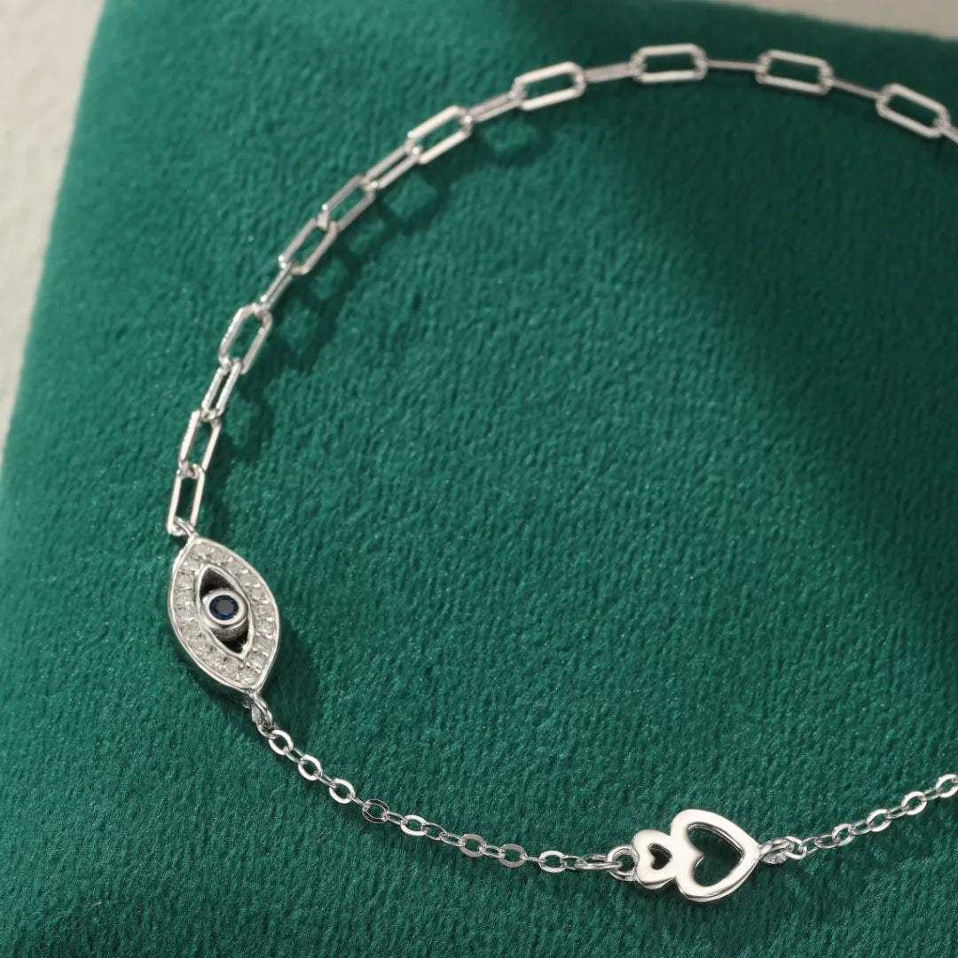Bracelet de cheville en argent 925 avec un fermoir en forme de cœur et un pendentif œil protecteur orné de zirconiums et d'une pierre bleue.