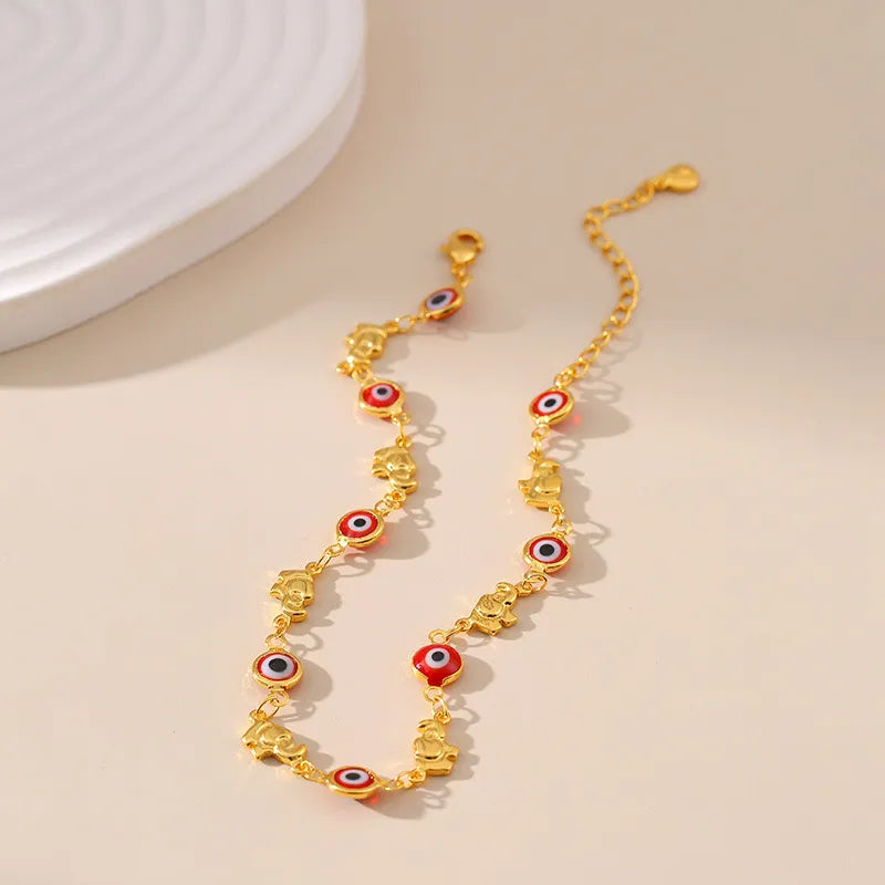 Bracelet de cheville doré or "Gardien Mystique" orné de multiples breloques œil du destin rouge et bleu et d'éléphants dorés.