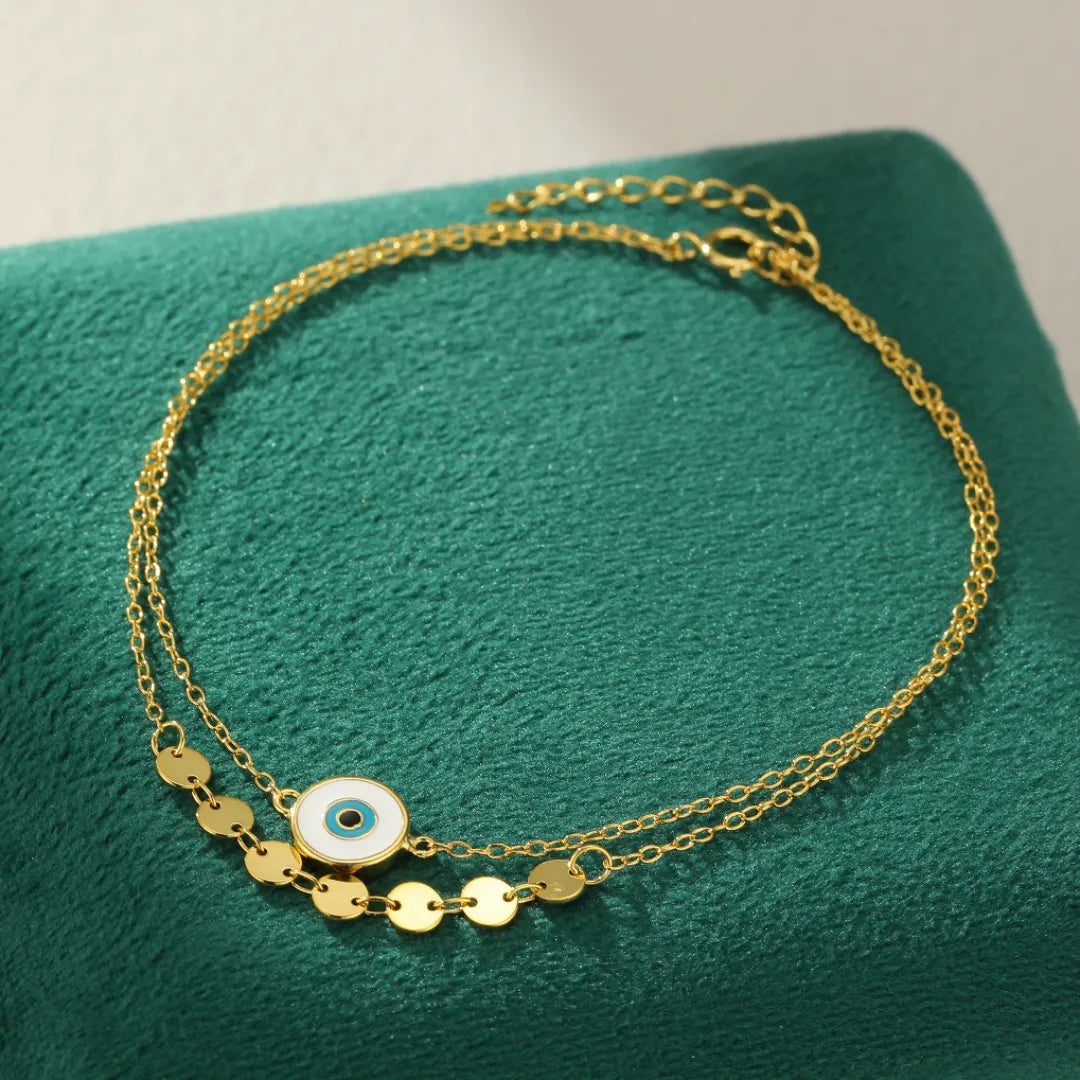 Bracelet de cheville double chaîne en argent 925 plaqué or, orné d'un pendentif œil bleu et blanc et de petites pampilles rondes.