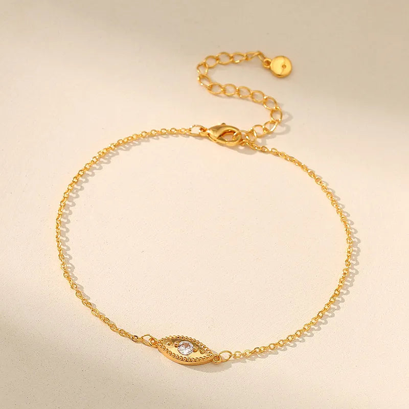 Bracelet de cheville doré à l'or orné d'un pendentif œil serti d'une pierre blanche et d'une chaîne fine ajustable.