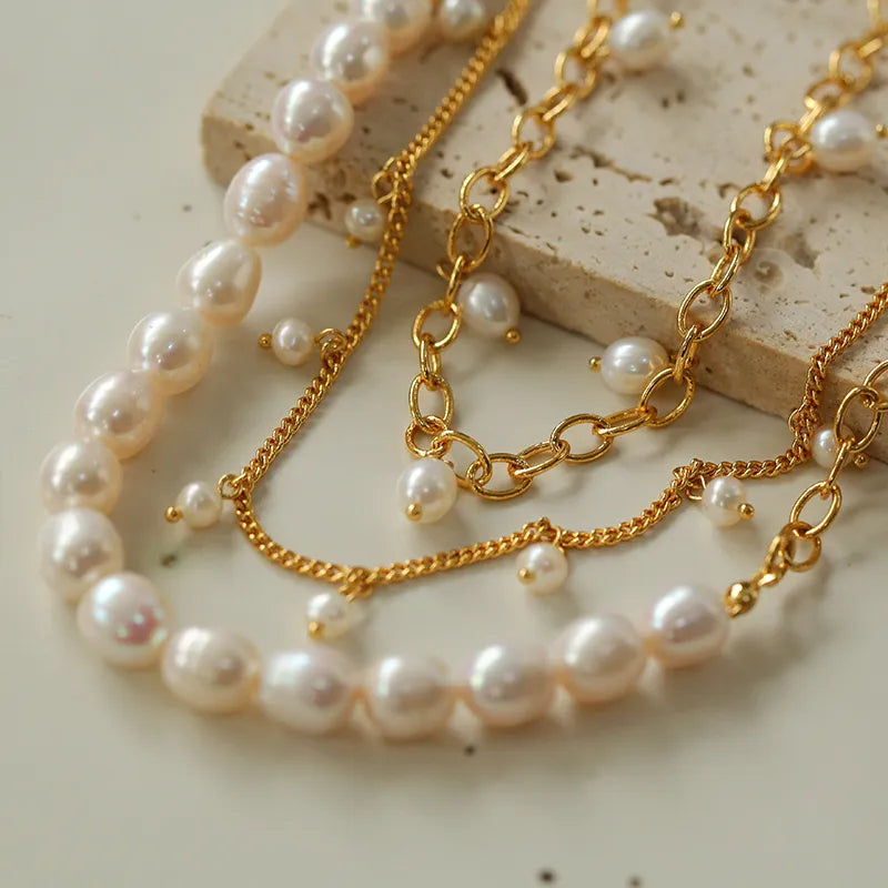 Bracelet de cheville doré à l'or avec des perles nacrées rondes et baroques, ornées de petites perles suspendues, sur un fond clair.