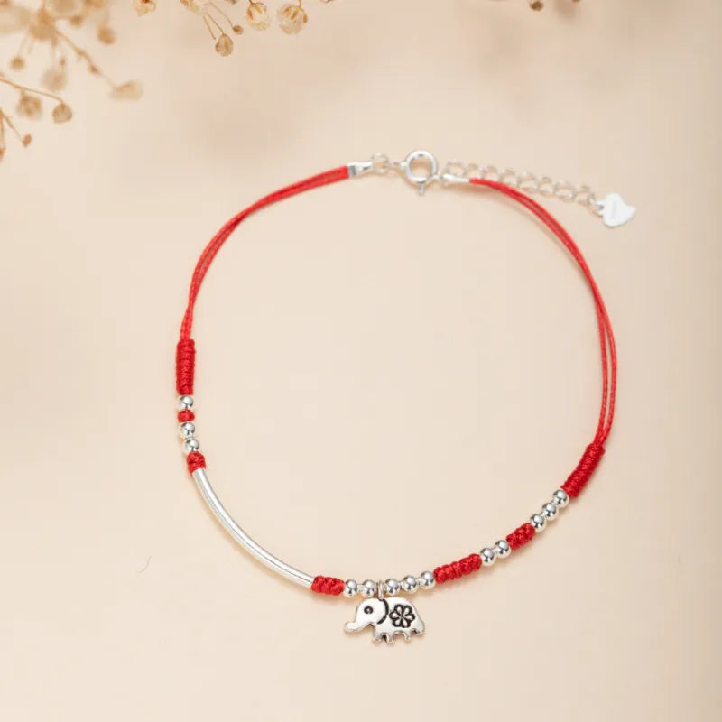 Bracelet de cheville "Petite Éléphant" en argent avec un cordon rouge et des perles argentées.