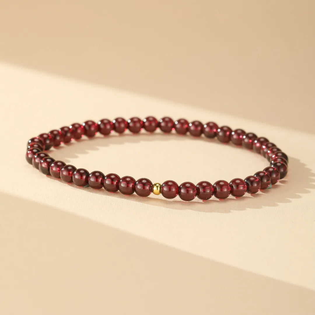 Bracelet en grenats naturels "Passion" avec une petite perle dorée au centre, sur fond clair.