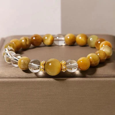 Bracelet "Énergie Vitale" fait de perles d'œil de tigre dorées et de perles de cristal de roche transparentes, avec des accents dorés entre les perles.