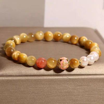 Bracelet "Élégance Discrète" avec des perles œil de tigre dorées, des perles roses, une perle sculptée et des perles de nacre blanches.