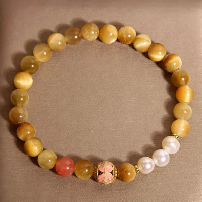 Bracelet "Élégance Discrète" avec des perles œil de tigre dorées, une perle rose, des perles blanches et une perle centrale décorée de motifs floraux roses et dorés.