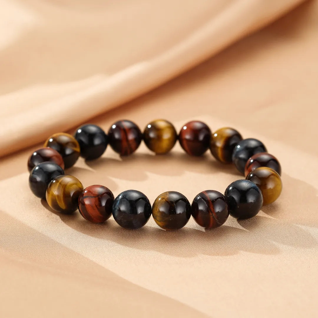Bracelet "Reflets d'Équilibre" en œil de tigre multicolore, composé de perles rondes aux teintes variées de brun, or, rouge et bleu, disposées sur un fond texturé.