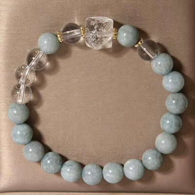 Bracelet "Clarté Apaisante" fait de perles rondes bleu pâle de jade et de perles de cristal de roche transparentes, avec une perle centrale brute de cristal de roche.