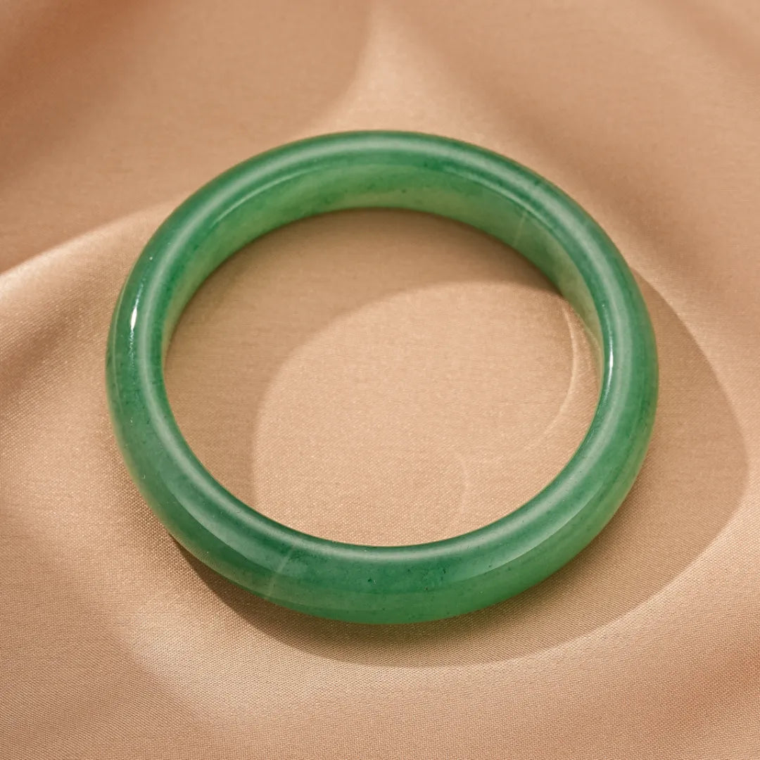Bracelet jonc Aventurine verte "Énergie Vitale" posé sur un tissu beige satiné.