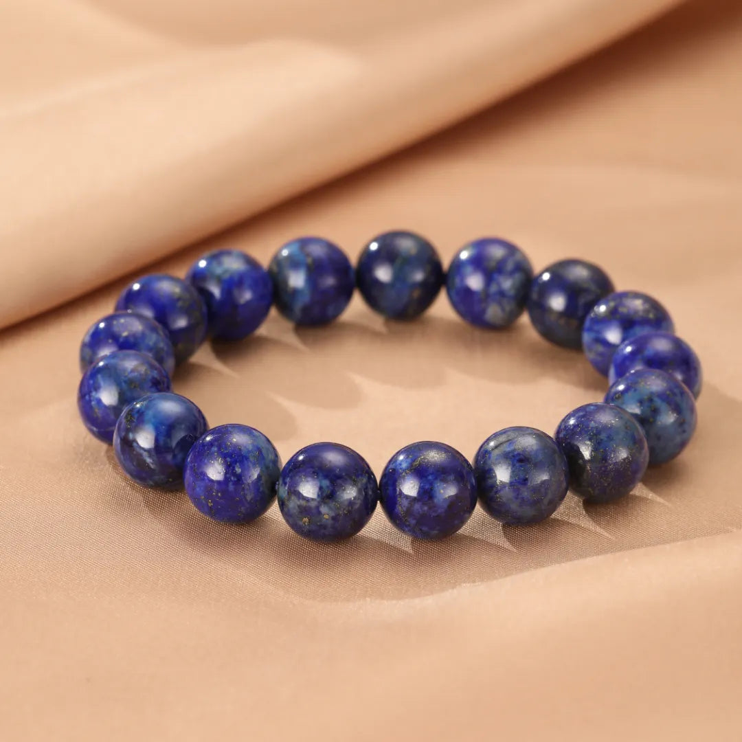 Bracelet perles de Lapis Lazuli "Bleu Profond" rondes et bleues intenses, posé sur un fond beige.