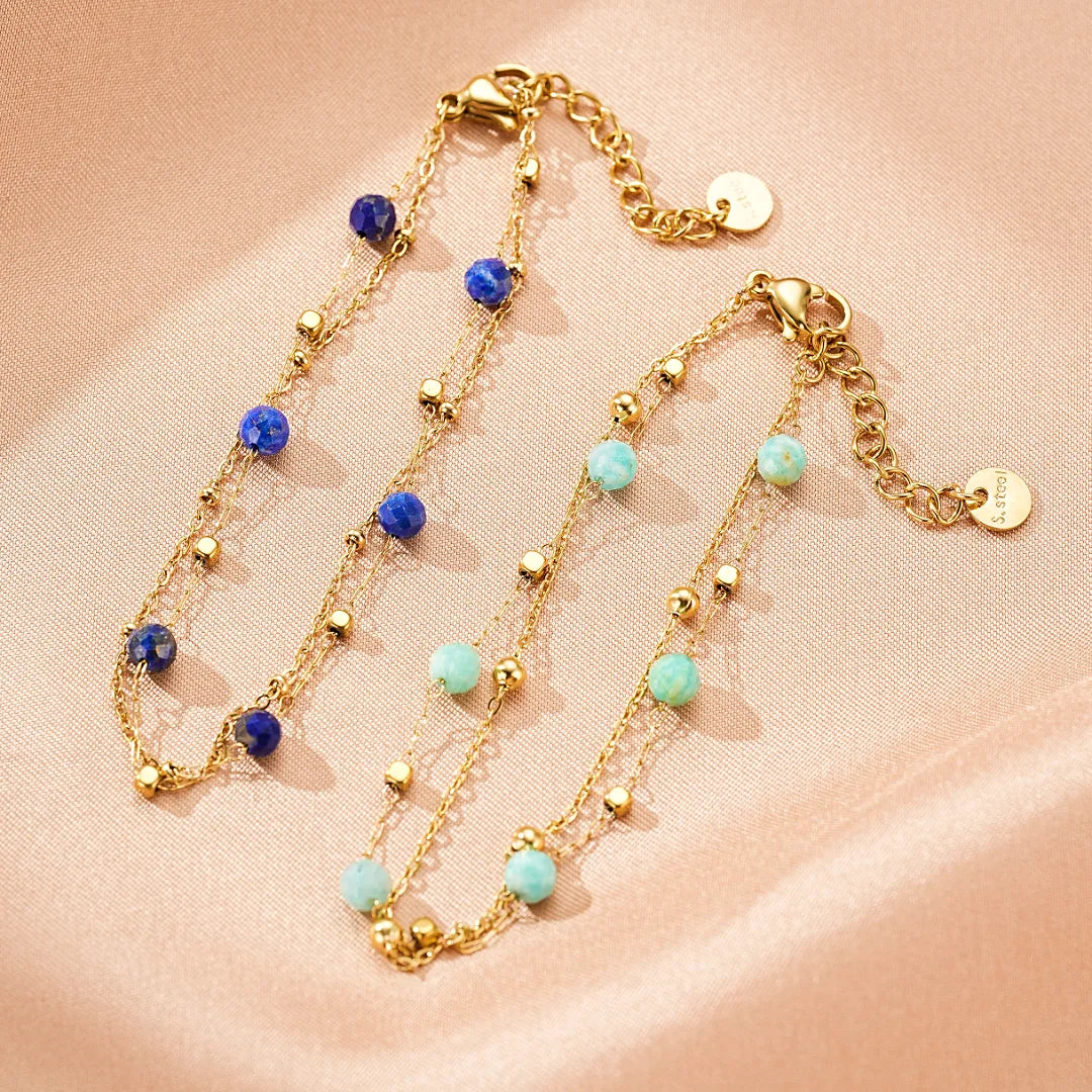Deux bracelets "Harmonie Fine" en plaqué or, l'un orné de perles facettées de lapis-lazuli bleu profond, l'autre de perles d'amazonite bleu-vert clair, tous deux agrémentés de petites perles dorées sur une fine chaîne.