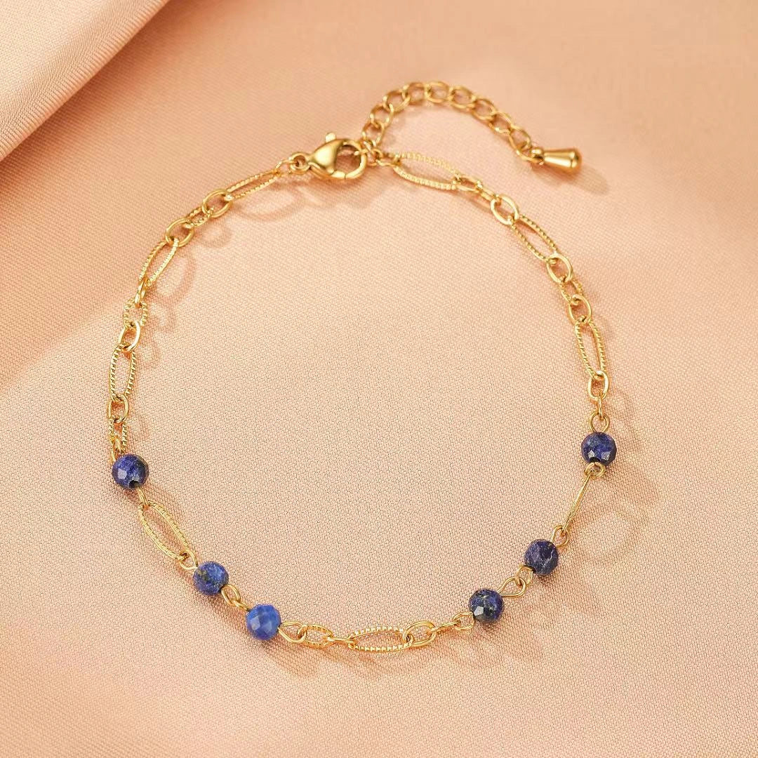 Bracelet fin en plaqué or, orné de perles naturelles de lapis lazuli bleu profond, avec une chaîne à maillons ovales texturés et une chaînette d'extension.